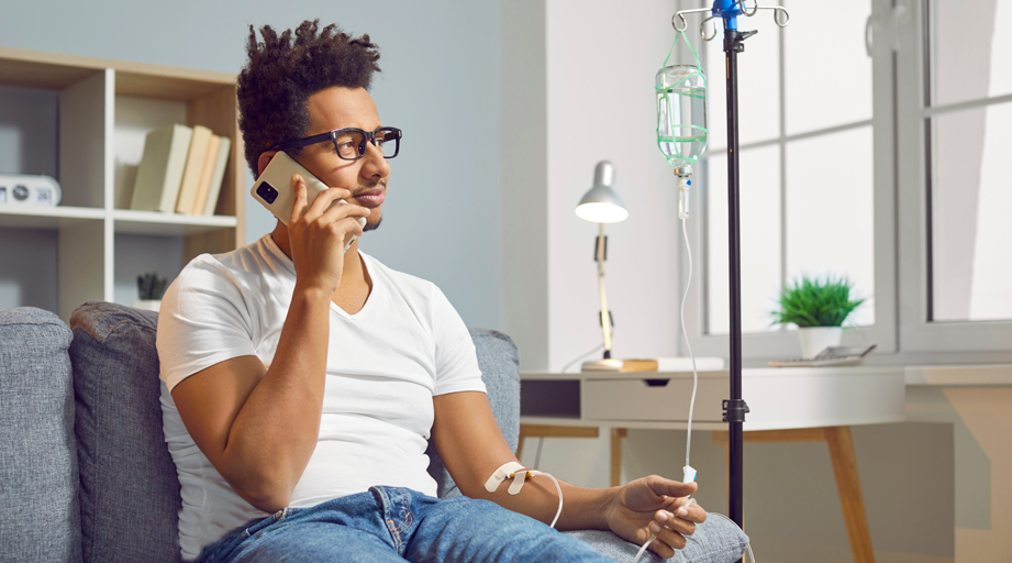 man sitting down, talking on the phone and receiving home infusion