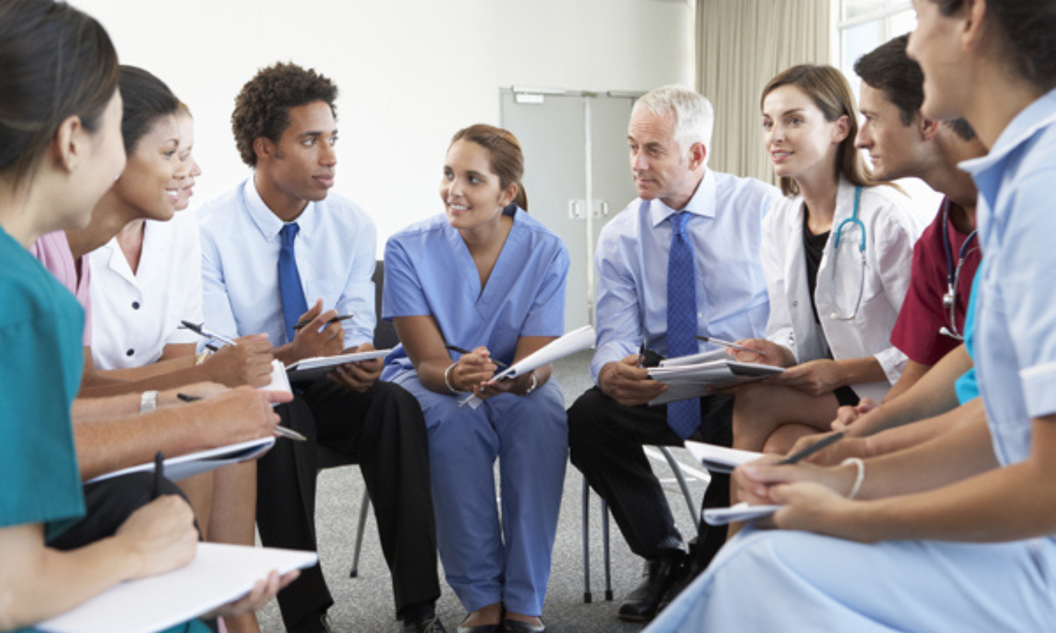 health care providers sitting in a circle, leaning in, and talking happily