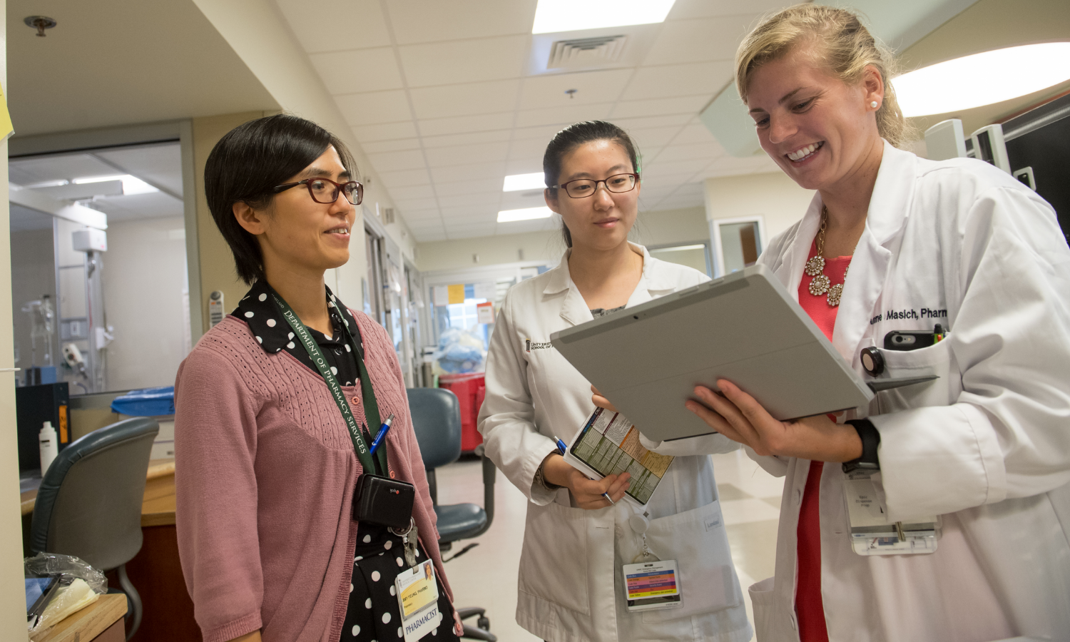health care providers smiling while looking at a tablet and helping a patient
